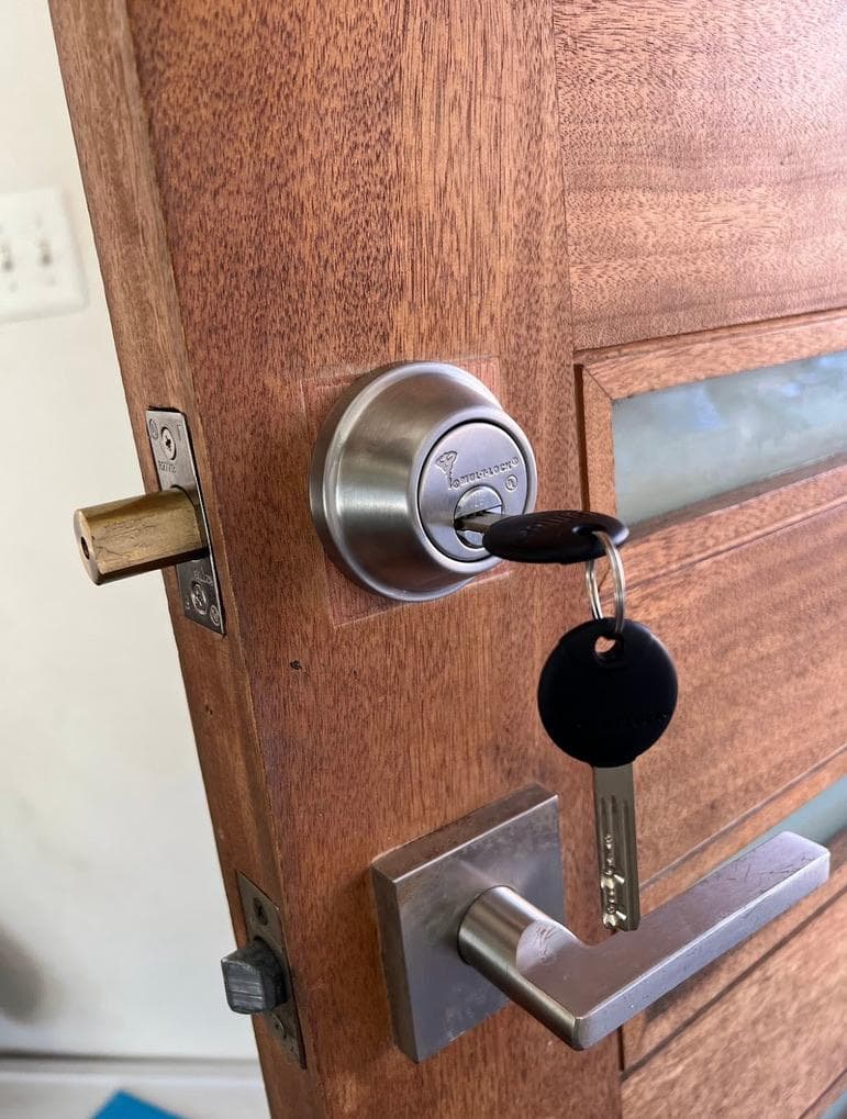 Mul-T-Lock deadbolt with keys in the cylinder on a wood door with a lever handle